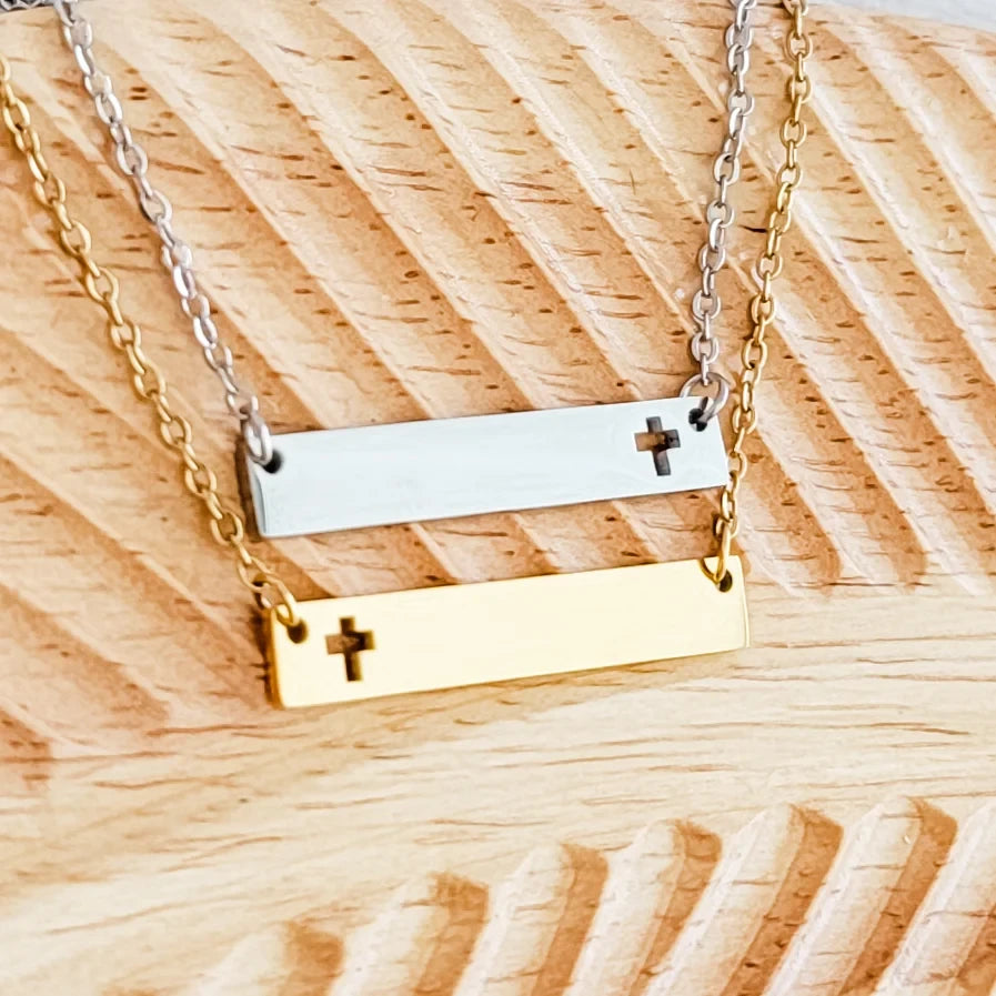 Roco Engraving custom silver and gold stainless steel cross bar necklaces with mirror finish on a wooden background