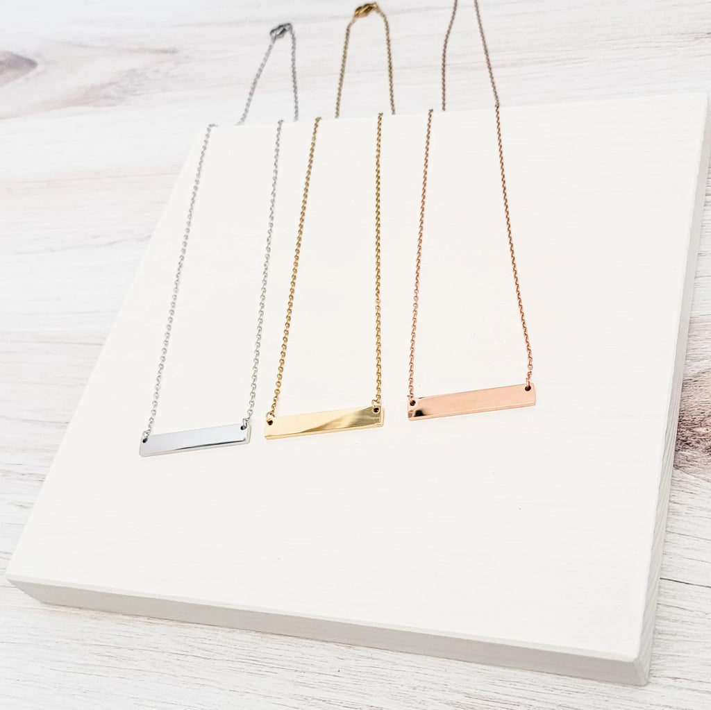 Roco Engraving custom bar necklaces in silver, gold, and rose gold stainless steel with mirror finish on white stand
