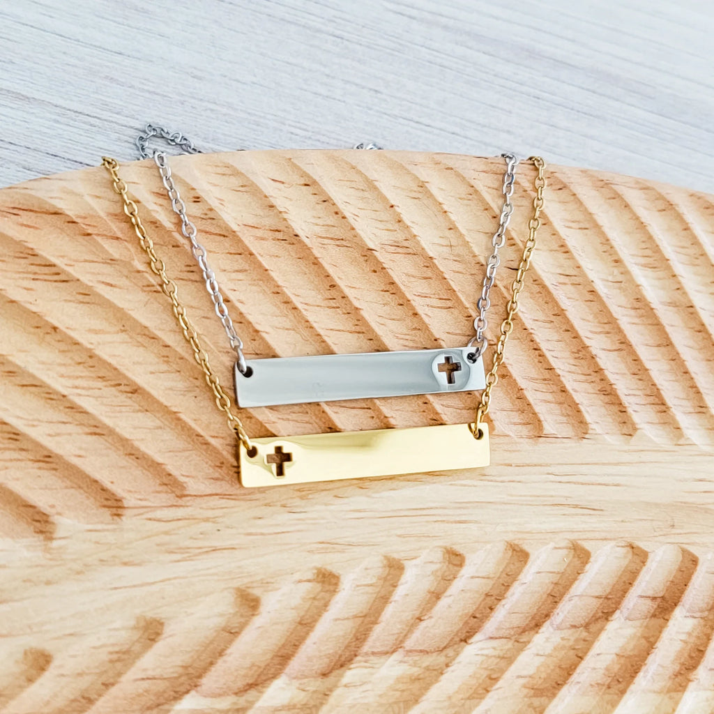 Roco Engraving silver and gold stainless steel cross bar necklaces with mirror finish on a wooden display