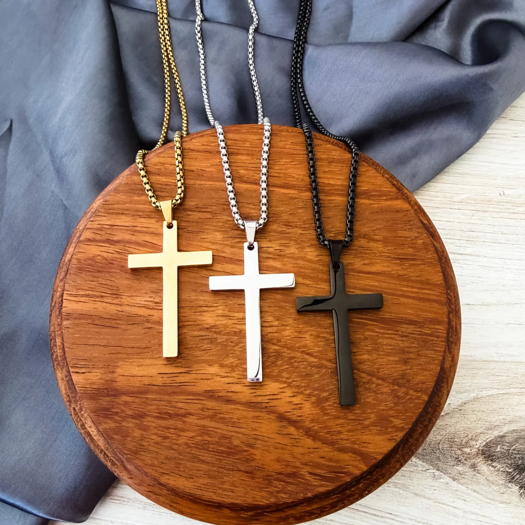 Roco Engraving gold, silver, and black stainless steel cross necklaces with polished finish on a wooden display