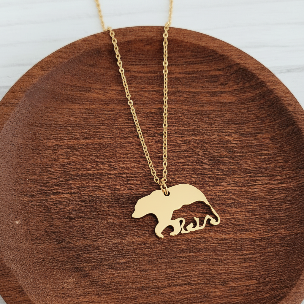 Roco Engraving gold bear and cub pendant necklace on a wooden dish
