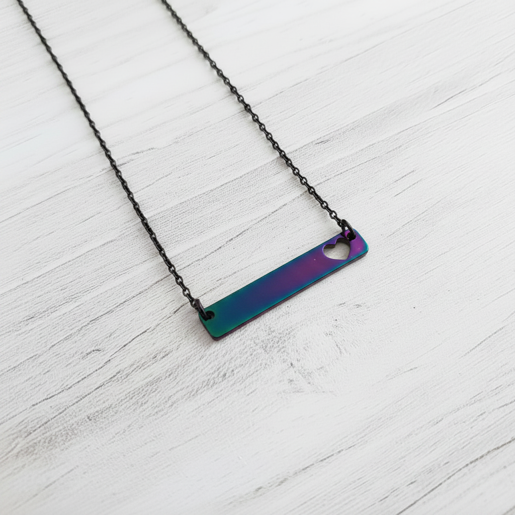 Roco Engraving iridescent stainless steel bar necklace with a heart cutout on a black chain against a white background
