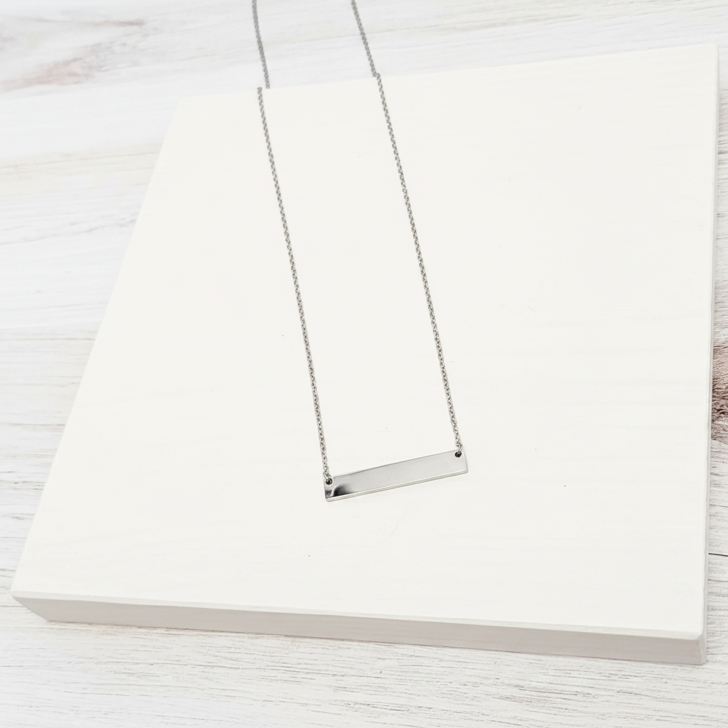 Roco Engraving silver bar necklace with a polished mirror finish on a white display block