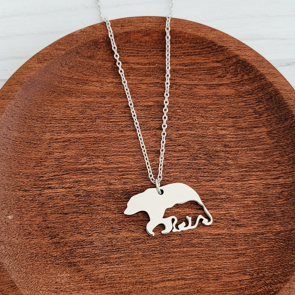 Roco Engraving silver bear and cub pendant necklace on a wooden dish, featuring a polished stainless steel finish.