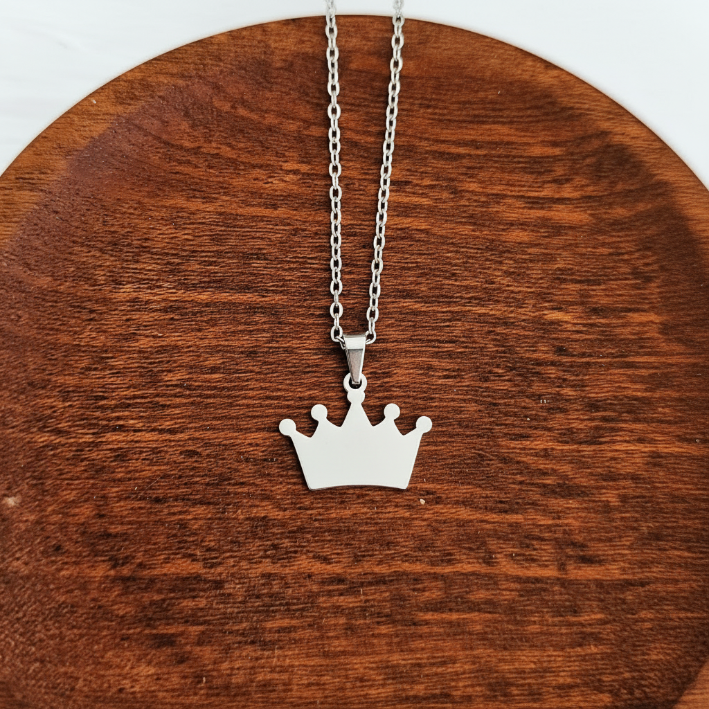 Roco Engraving silver crown pendant necklace on a wooden display, featuring a polished stainless steel finish.