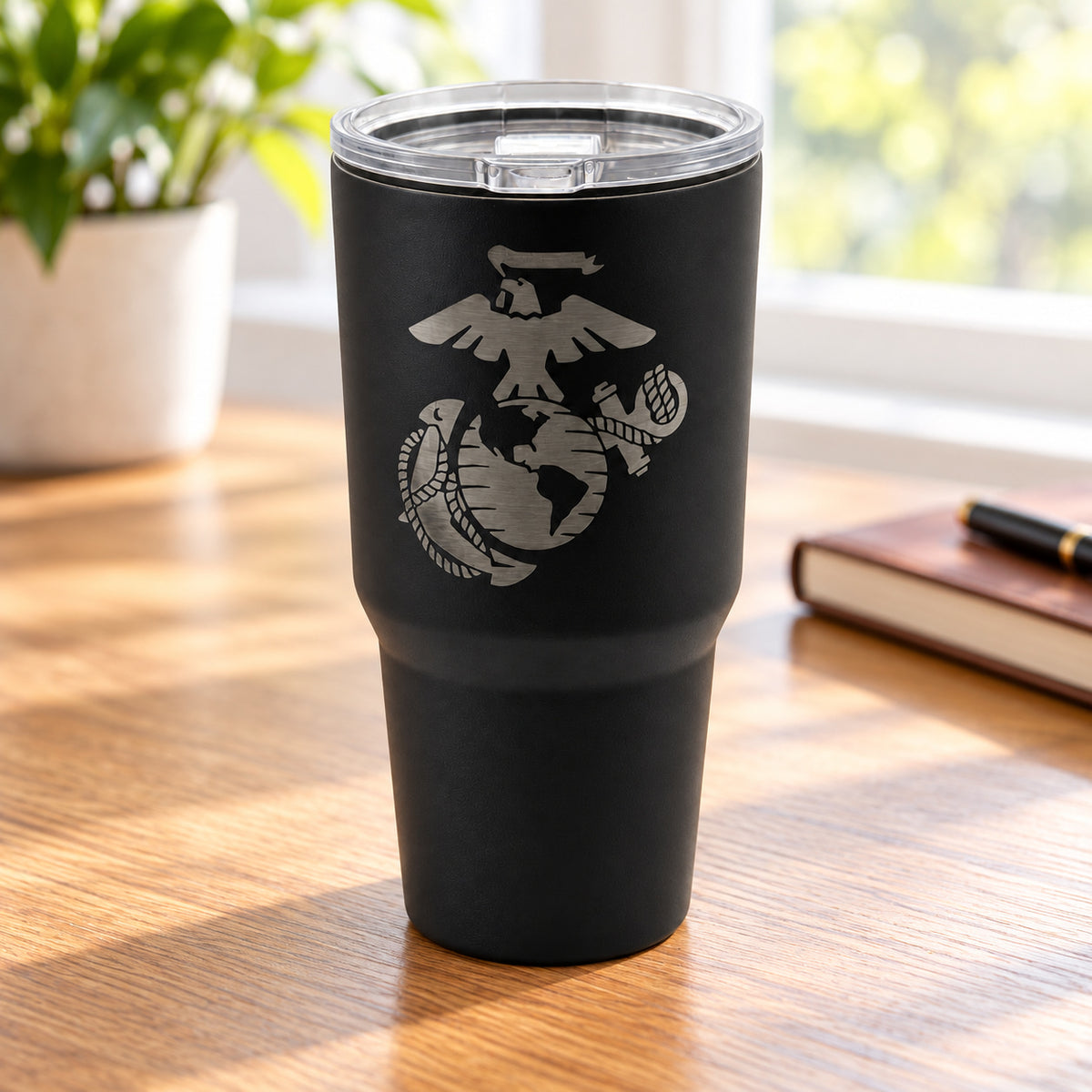 Black 30oz MakerFlo tumbler engraved with the Marines Emblem design, on a tabletop