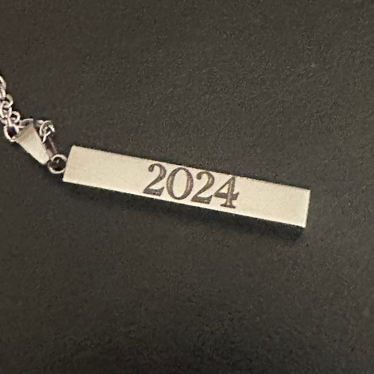 A real silver-tone pendant engraved with 2024 on a dark background